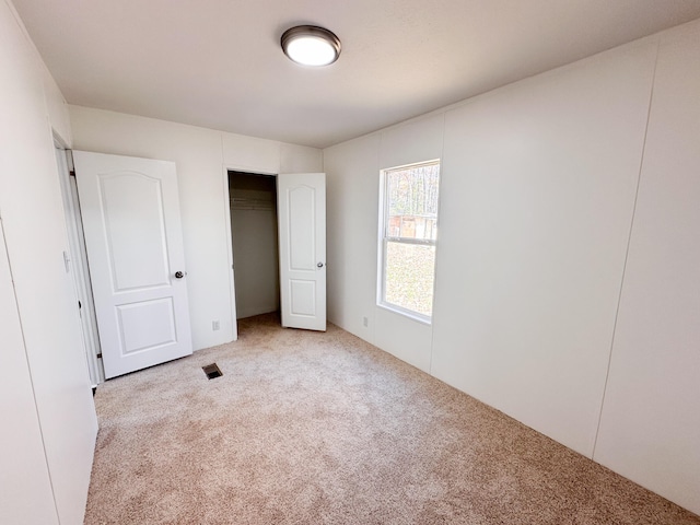 unfurnished bedroom with light carpet and a closet