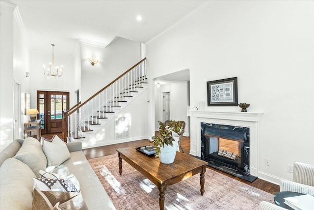 living room with a premium fireplace, a towering ceiling, wood-type flooring, and ornamental molding