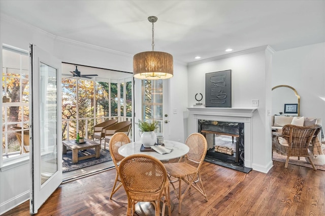 dining area with dark hardwood / wood-style floors, ceiling fan, a premium fireplace, and ornamental molding