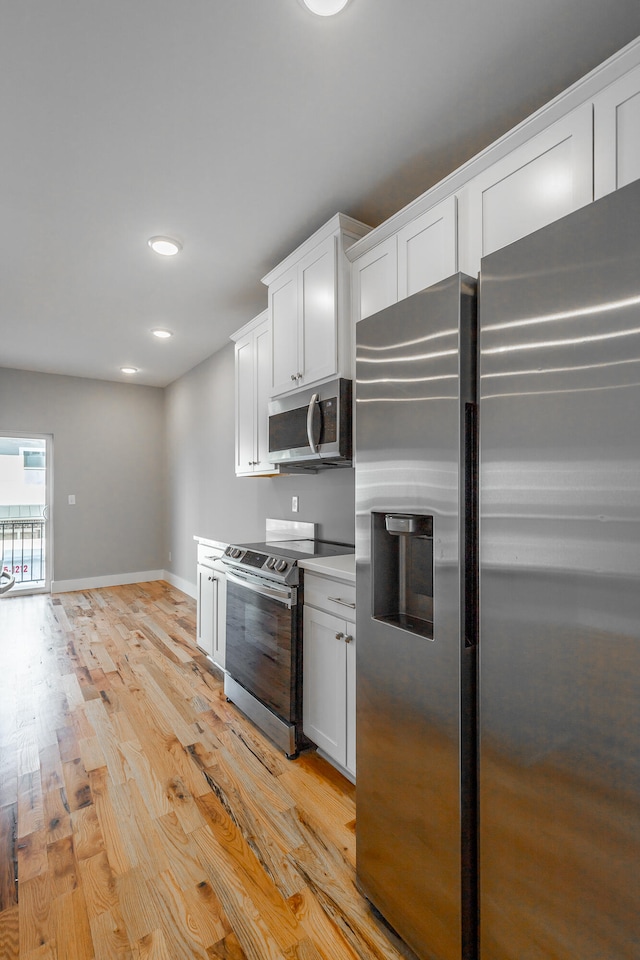 kitchen with white cabinetry, stainless steel appliances, and light hardwood / wood-style flooring