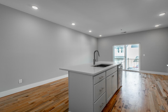 kitchen with dishwasher, light wood-type flooring, a center island with sink, and sink