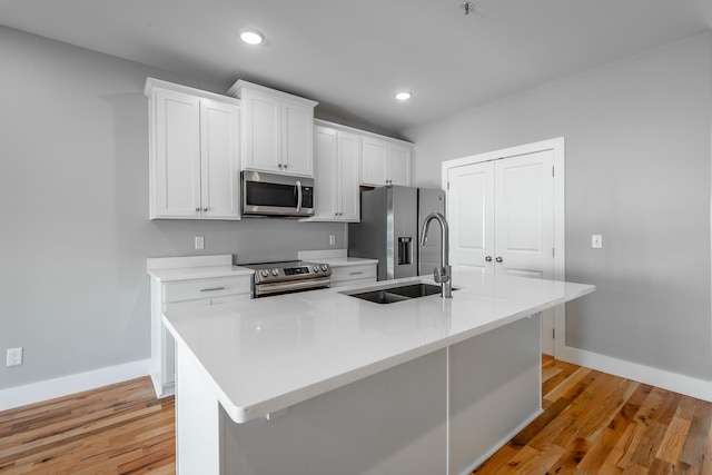 kitchen featuring sink, light hardwood / wood-style flooring, a center island with sink, white cabinets, and appliances with stainless steel finishes