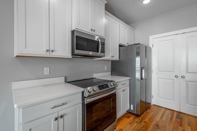 kitchen featuring white cabinets, stainless steel appliances, and light wood-type flooring