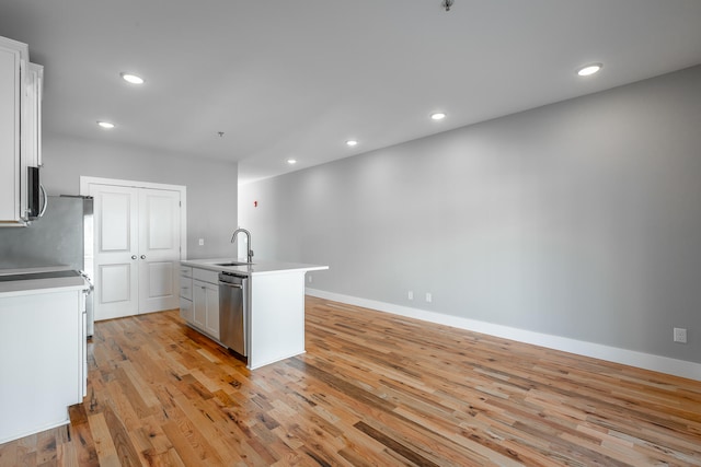 kitchen with white cabinetry, a center island with sink, stainless steel appliances, and light hardwood / wood-style floors