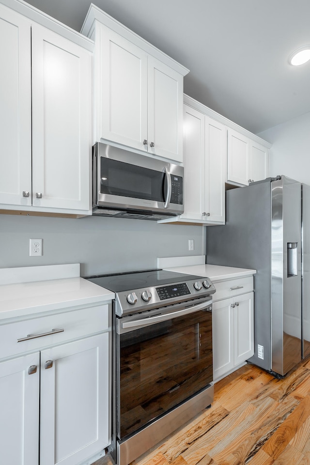 kitchen featuring white cabinets, light hardwood / wood-style floors, and appliances with stainless steel finishes