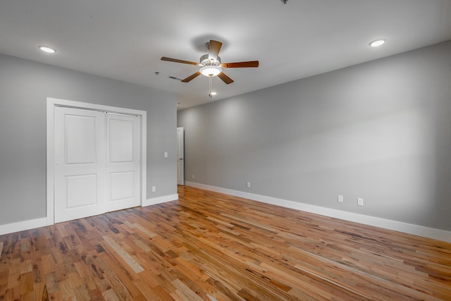 unfurnished bedroom featuring ceiling fan, light hardwood / wood-style floors, and a closet