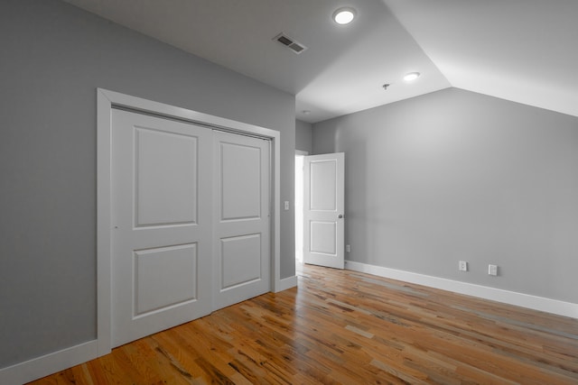 unfurnished bedroom with vaulted ceiling, light hardwood / wood-style flooring, and a closet