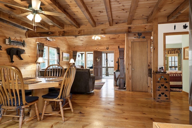 dining area featuring wood ceiling, wooden walls, light hardwood / wood-style floors, and vaulted ceiling with beams