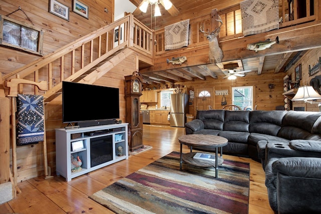 living room featuring hardwood / wood-style flooring, a high ceiling, ceiling fan, and wood walls