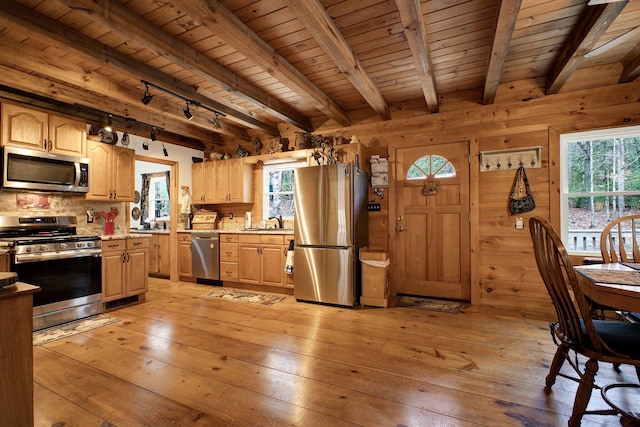 kitchen with appliances with stainless steel finishes, wooden walls, light hardwood / wood-style floors, and beam ceiling