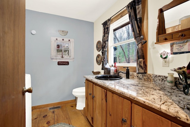 bathroom featuring vanity, wood-type flooring, and toilet