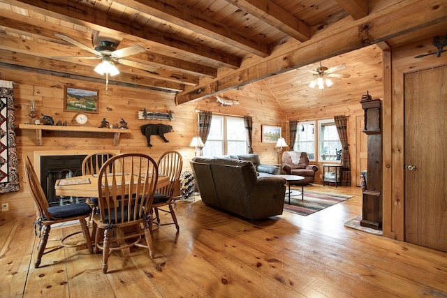 dining room featuring beamed ceiling, wooden ceiling, wooden walls, and light wood-type flooring