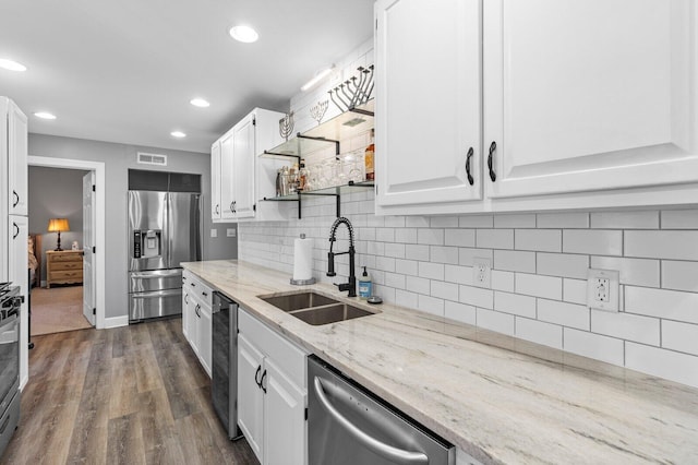 kitchen featuring dark hardwood / wood-style flooring, light stone counters, stainless steel appliances, sink, and white cabinets