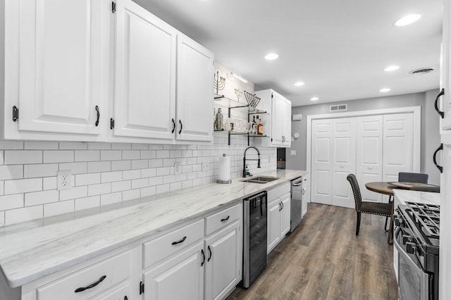 kitchen featuring sink, dark hardwood / wood-style floors, appliances with stainless steel finishes, white cabinetry, and beverage cooler