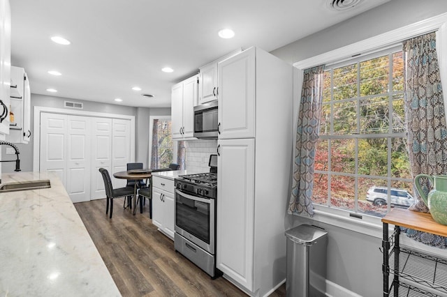 kitchen featuring stainless steel appliances, white cabinetry, a healthy amount of sunlight, and sink