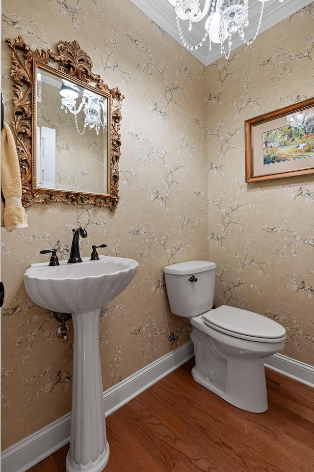 bathroom with hardwood / wood-style flooring, toilet, crown molding, and a chandelier