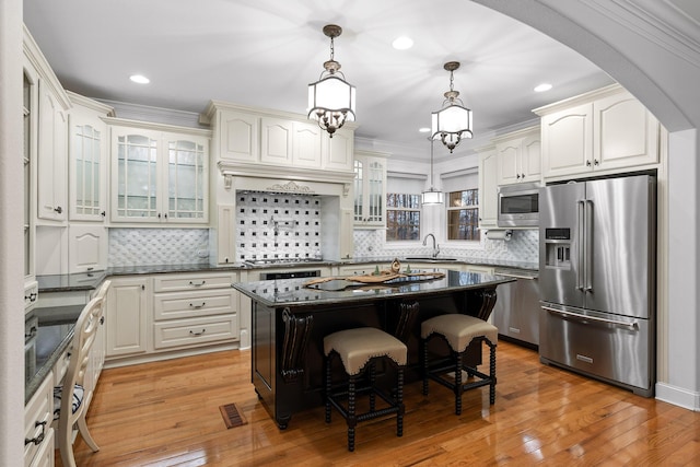 kitchen featuring a kitchen island, ornamental molding, appliances with stainless steel finishes, light hardwood / wood-style floors, and a breakfast bar area