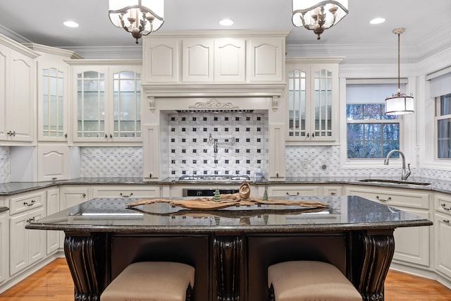 kitchen with a center island, backsplash, dark stone counters, sink, and a kitchen bar