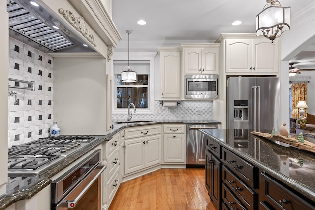 kitchen with decorative backsplash, custom exhaust hood, stainless steel appliances, sink, and pendant lighting