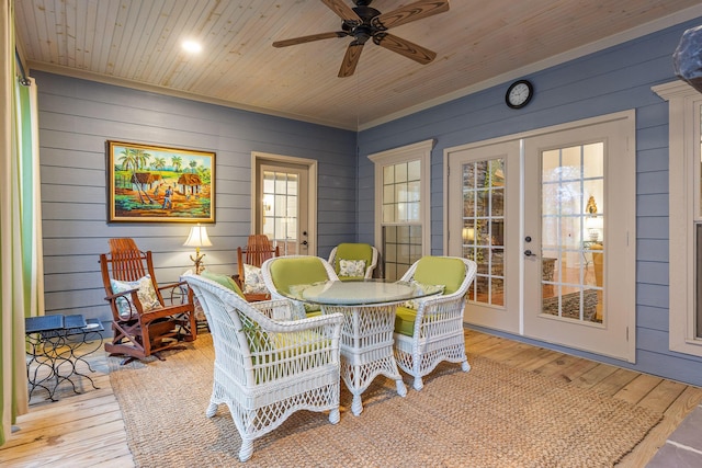 dining room with wood walls, french doors, and light hardwood / wood-style flooring