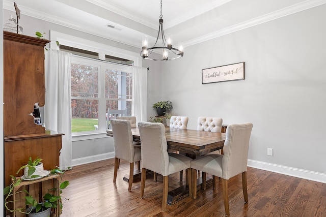 dining space featuring dark wood-type flooring, crown molding, and an inviting chandelier