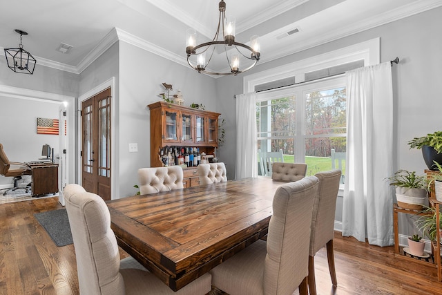 dining space featuring an inviting chandelier, a healthy amount of sunlight, dark hardwood / wood-style floors, and crown molding