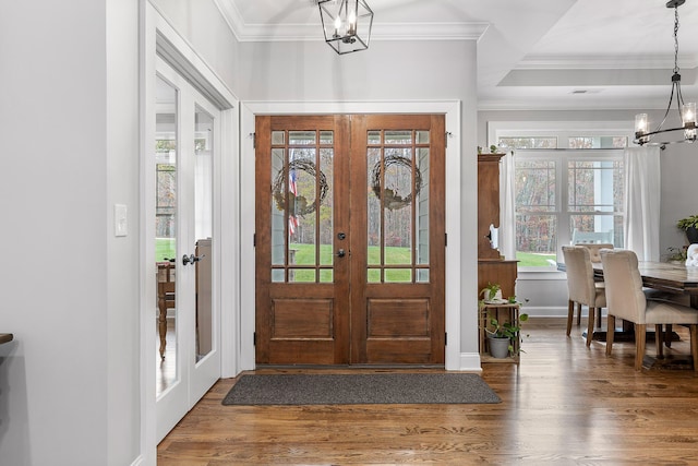 entryway featuring dark hardwood / wood-style floors, ornamental molding, french doors, and an inviting chandelier