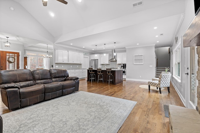 living room with ceiling fan with notable chandelier, plenty of natural light, light hardwood / wood-style flooring, and lofted ceiling