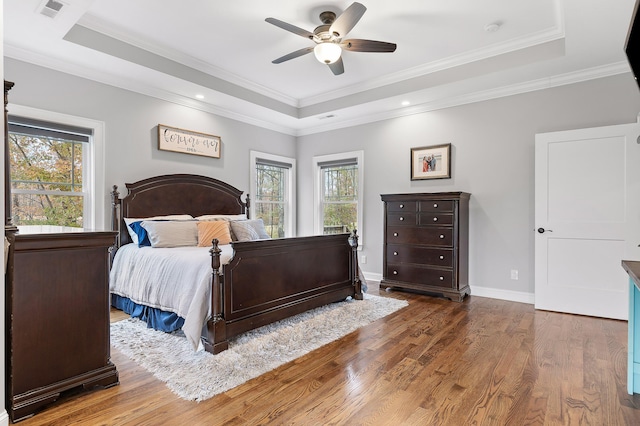 bedroom featuring a raised ceiling, ceiling fan, dark hardwood / wood-style flooring, and crown molding