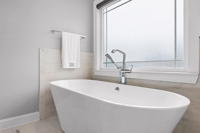 bathroom with a wealth of natural light, tile patterned flooring, sink, and a bath