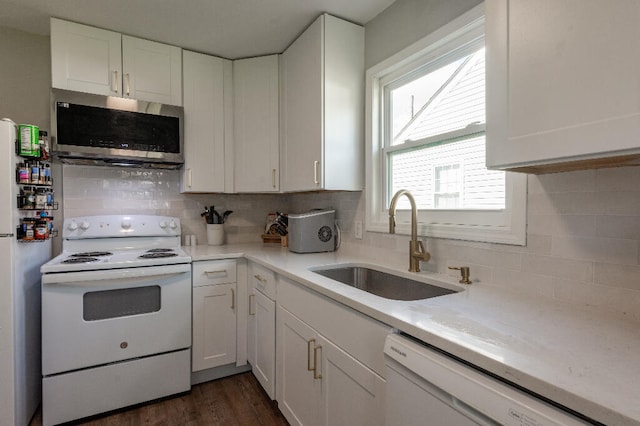 kitchen with white appliances, sink, dark hardwood / wood-style floors, decorative backsplash, and white cabinetry