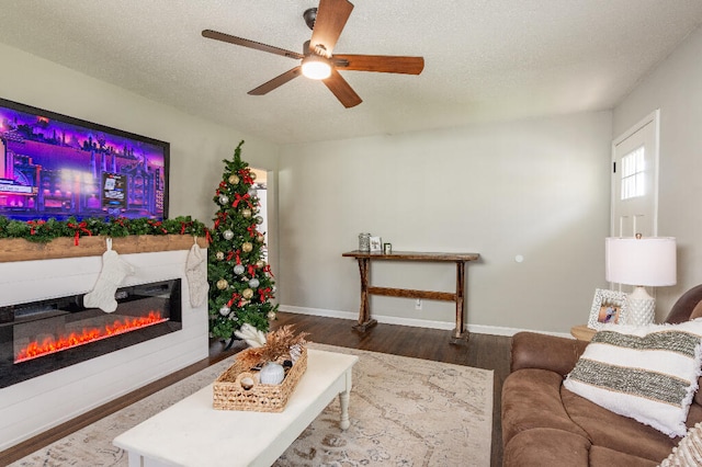 living room with a textured ceiling, ceiling fan, and dark wood-type flooring