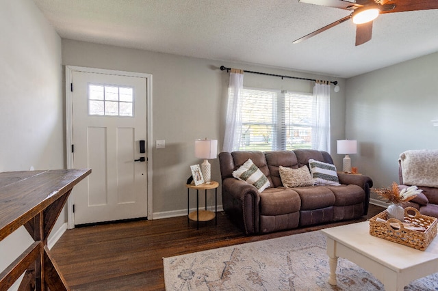 living room featuring ceiling fan, dark hardwood / wood-style flooring, and a textured ceiling