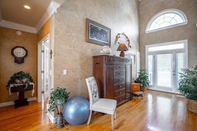 entrance foyer featuring wood-type flooring, crown molding, a high ceiling, and french doors