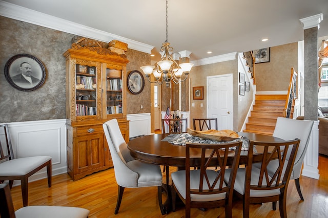 dining room featuring a chandelier, light hardwood / wood-style floors, ornate columns, and ornamental molding