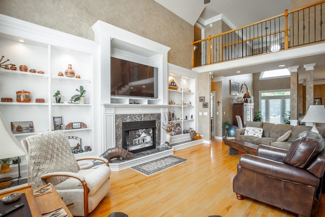 living room with built in features, a high end fireplace, high vaulted ceiling, crown molding, and hardwood / wood-style flooring