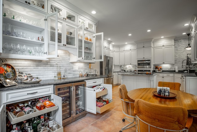 kitchen featuring light tile patterned floors, tasteful backsplash, white cabinetry, stainless steel appliances, and beverage cooler