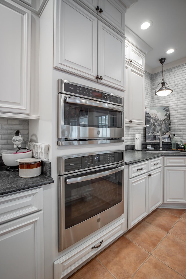 kitchen with decorative backsplash, decorative light fixtures, and white cabinets