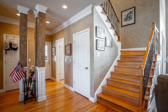 stairs featuring hardwood / wood-style floors, ornate columns, and ornamental molding