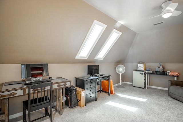 carpeted office featuring lofted ceiling with skylight and ceiling fan