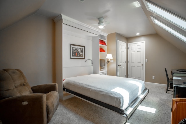 carpeted bedroom with lofted ceiling with skylight and ceiling fan