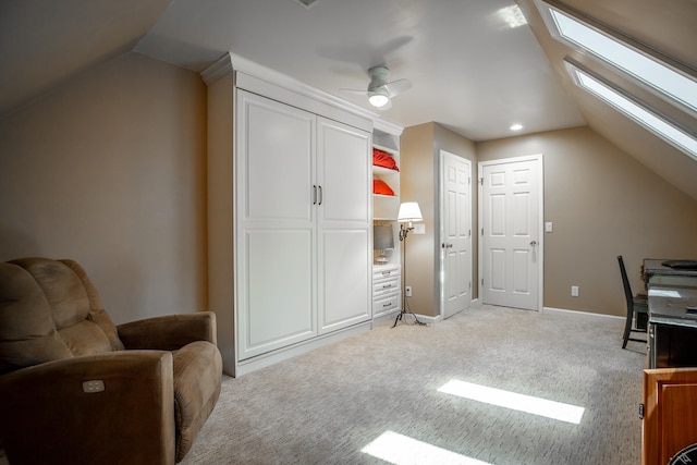 carpeted home office featuring lofted ceiling with skylight and ceiling fan