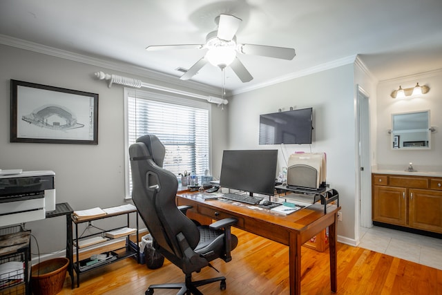 home office featuring ceiling fan, sink, light hardwood / wood-style floors, and ornamental molding