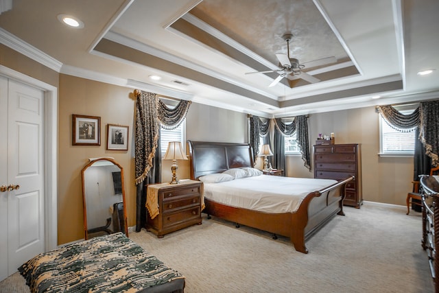 carpeted bedroom with a raised ceiling, ceiling fan, and ornamental molding