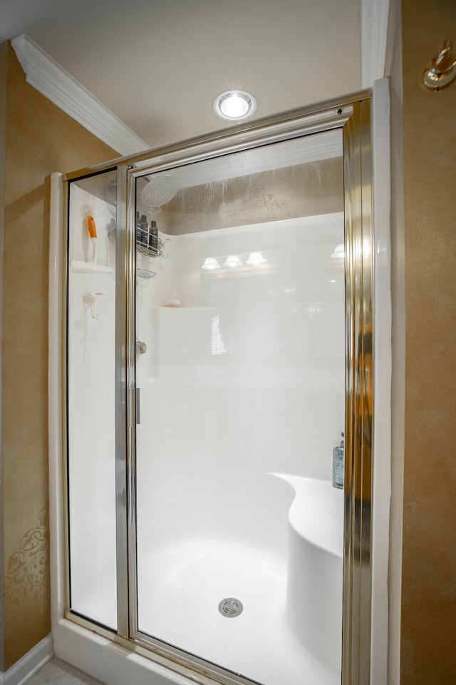 bathroom featuring a shower with shower door and ornamental molding