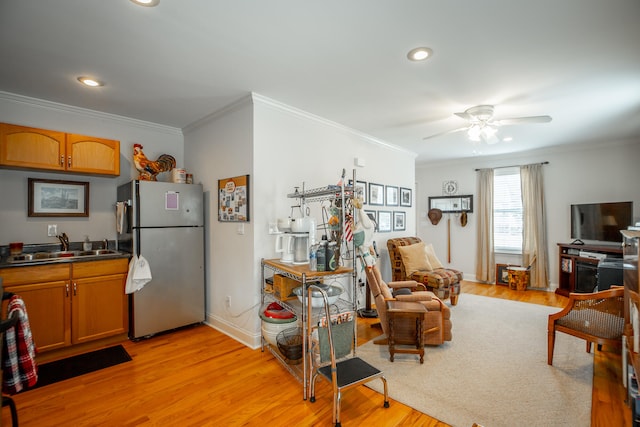 interior space featuring light hardwood / wood-style floors, ceiling fan, ornamental molding, and sink