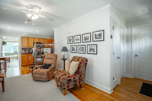 living area featuring crown molding, ceiling fan, and light hardwood / wood-style floors