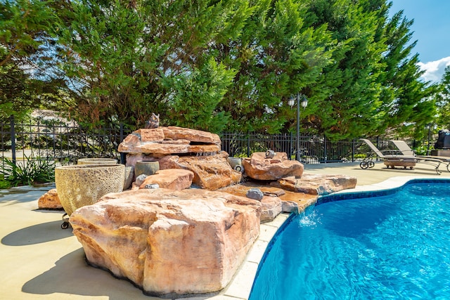 view of swimming pool with pool water feature and a patio area