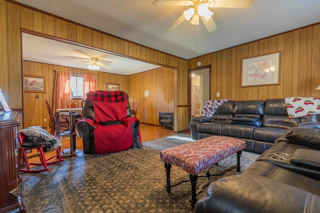 living room with wood walls, ceiling fan, and a textured ceiling