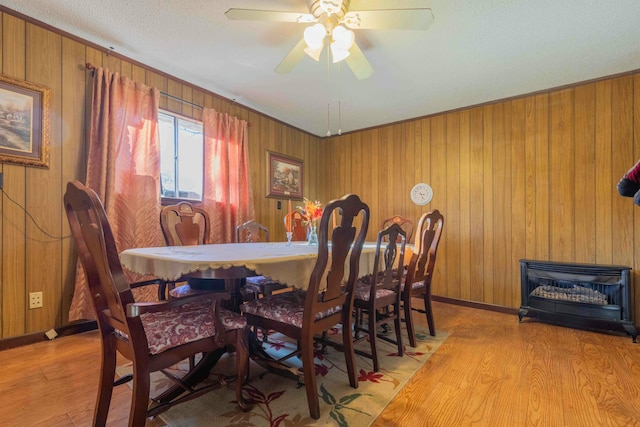 dining space featuring wood walls, ceiling fan, and light hardwood / wood-style floors